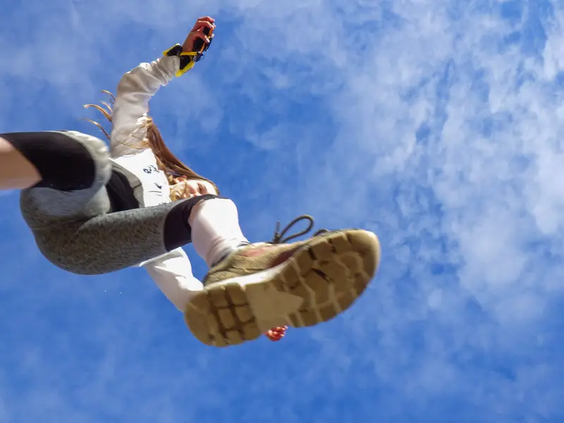Kind springt over de camera heen, gefotografeerd vanuit kikkerperspectief